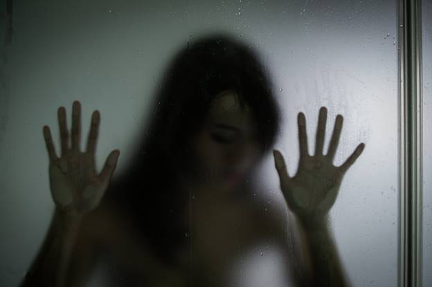 A woman's silhouette is blurred behind textured glass. The image conveys a sense of entrapment and distress, as suggested by the accompanying article on civil and criminal law.